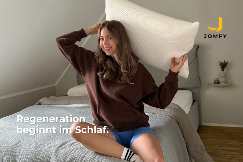 Sportliche Frau mit JOMFY DREAM Kissen im Schlafzimmer – Fokus auf Regeneration und erholsamen Schlaf
