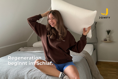 Sportliche Frau mit JOMFY DREAM Kissen im Schlafzimmer – Fokus auf Regeneration und erholsamen Schlaf
