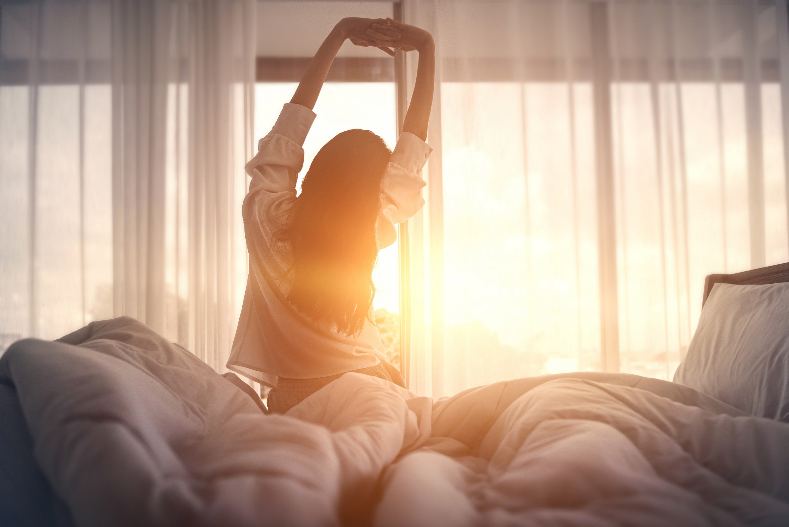 Frau entspannt auf einem Bett – Symbolbild für erholsamen Schlaf mit JOMFY